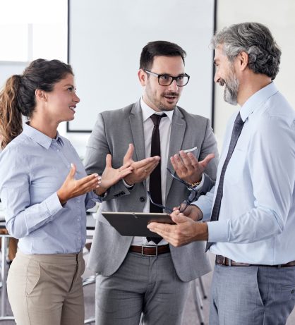 A portrait of a young and senior smiling businesspeople holding a tablet during a meeting and presentation in the office. Business concept
